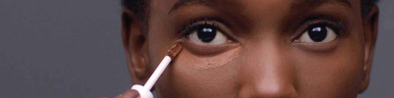 Immagine illustrativa banner tutorial make-up correttore   primo piano di una donna che applica il correttore sotto gli occhi