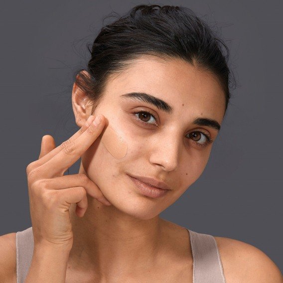 Donna che applica il fondotinta sullo zigomo