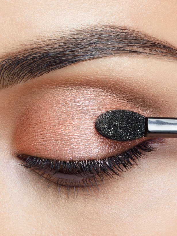 Donna che applica ombretto color bronzo sulla palpebra dalla palette The Blushed Nudes