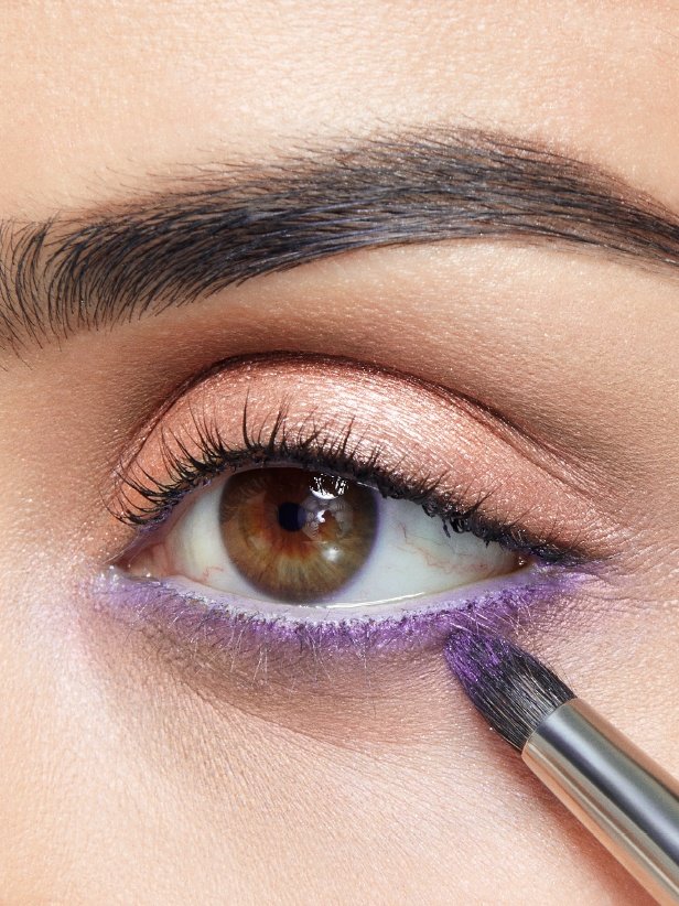 Donna che applica l'ombretto in gel-crema Eyestudio Color Tattoo 24HR nella nuance "Painted Purple" sulla rima palpebrale inferiore